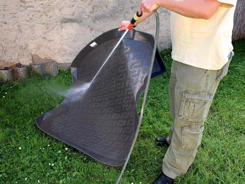 Kofferraumwanne abspritzen Eine Kofferraumwanne wir von einem Mann abgespritzt.