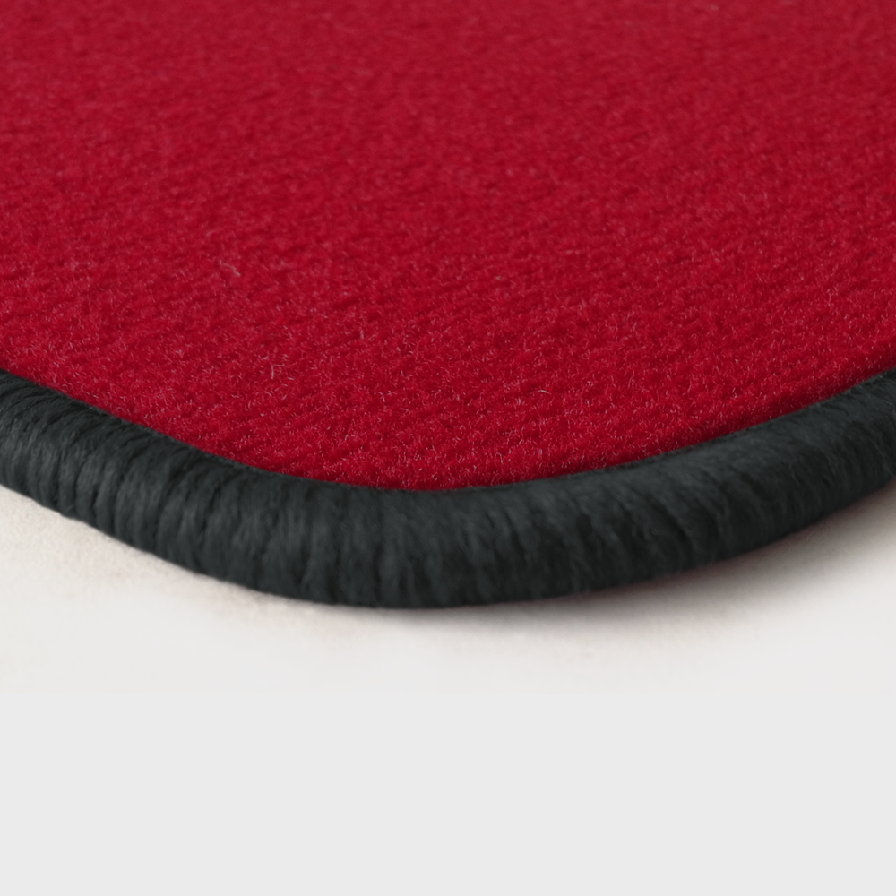 Eine Ecke als Beispiel einer Fussmatte Velours rot mit Rand in dunkelgrau.