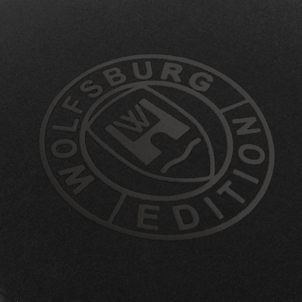 Das Wolfsburg Editions Logo auf einem schwarzen Teppich und das Logo ist in anthrazit.